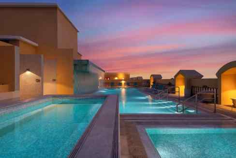 Rooftop swimming pool at Doha Al Mansoura Aparthotel with stunning sunset view and relaxing ambiance.