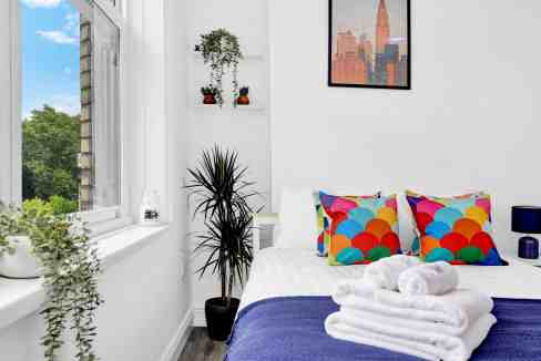 Modern bedroom with colorful cushions and natural light.