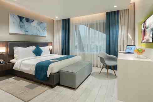 A spacious hotel room at Muscat Al Ghubrah Aparthotel featuring contemporary design, comfortable bed.