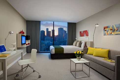 Modern Melbourne East End Aparthotel room with city skyline view.