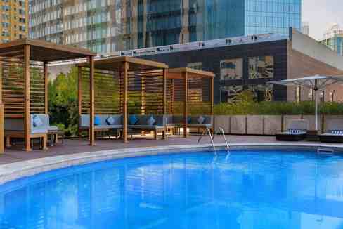 Poolside lounge area with cabanas and city skyline at Doha West Bay Aparthotel.