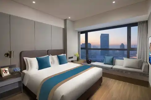 Hotel room with large window overlooking Changchun skyline and cityscape.
