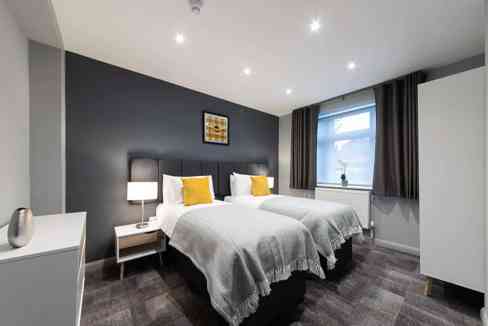 Contemporary bedroom in Cardiff Pontcanna with twin beds, dark accent wall, and natural light, perfe.