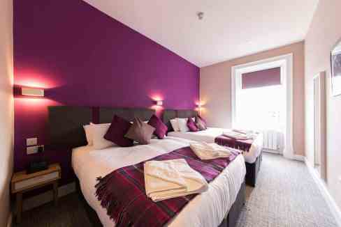 Modern bedroom in Edinburgh Hanover St Apartments with vibrant purple accent wall.