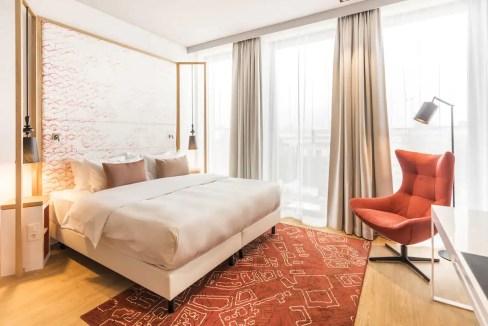 Comfortable hotel room with a large bed, natural light, and contemporary furnishings in Berlin Mitte.