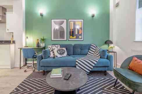 Stylish living space featuring a blue sofa, contemporary decor, and vibrant wall art in Tower Bridge.