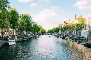 Amsterdam canal view with historic buildings and boats on a sunny day.