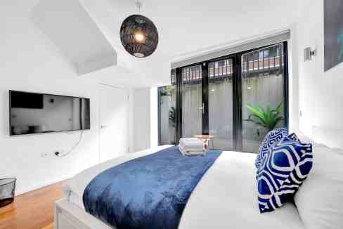 Bright, contemporary bedroom in Hoxton Bevenden St with large windows and modern furnishings.