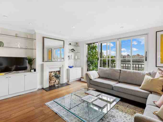 Bright living room with large windows overlooking the Thames. Modern decor with cozy sofa and stylis.