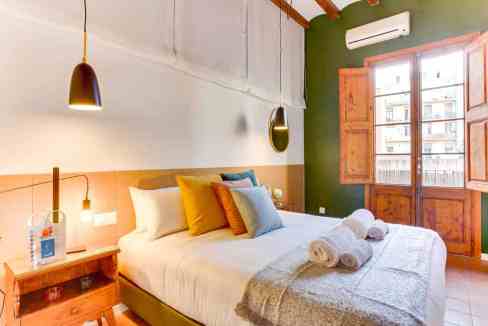 Bedroom in Barcelona Marina Apartments with cozy decor and large window.