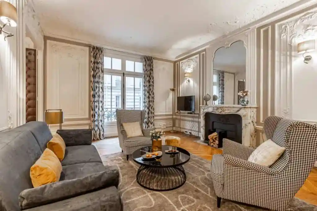 Stylish living space featuring vintage furniture, fireplace, and natural light at Rue la Boetie Apar.