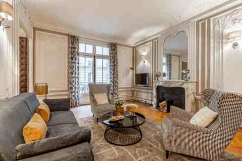 Stylish living space featuring vintage furniture, fireplace, and natural light at Rue la Boetie Apar.
