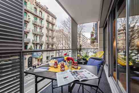 Balcony with outdoor seating and flowers at Calabria Apartments, Barcelona.