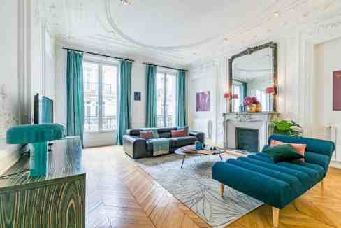 Spacious living room featuring high ceilings, large windows, and stylish furniture.