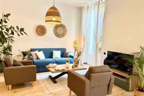 Contemporary living space featuring a blue sofa, armchairs, and decorative plants.