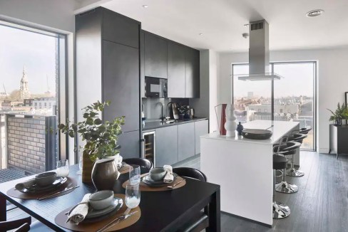 Modern kitchen with black cabinetry and large windows in Shoreditch. Bright, stylish space with city.