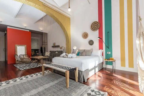 Stylish loft bedroom with colorful wall stripes and eclectic decor in Barcelona La Plata.