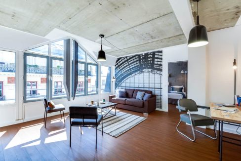 Spacious living area in Rue de Milan Apartments featuring large windows, contemporary furniture, and.