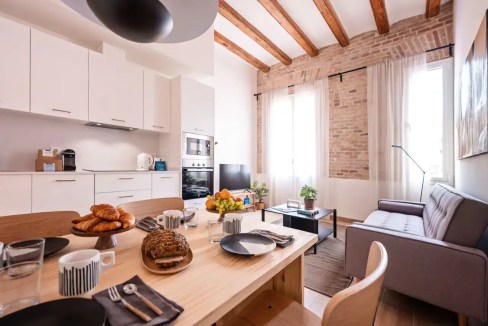 Bright Barcelona apartment living room with dining table, natural light, and contemporary decor.