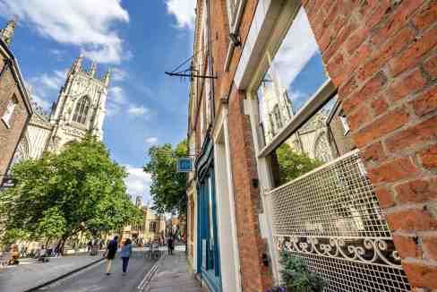 View of historic High Petergate street with York Minster in the background, UK.