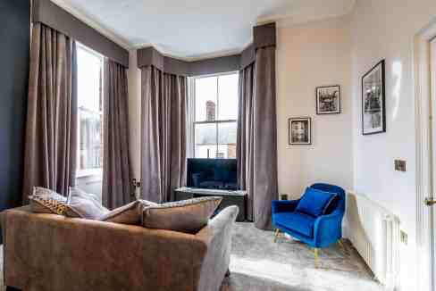 Cozy living room with large windows, elegant curtains, and modern furniture in Lady Peckett's Yard A.