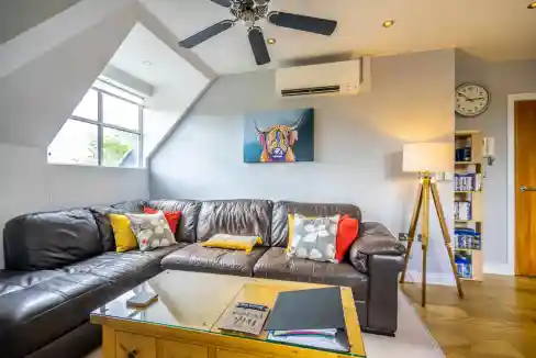 Modern living room with comfortable leather sofa and colorful cushions, bright natural light, and st.