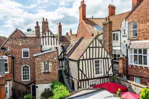 Historic Tudor-style row houses with brick facades and timber framing in a vibrant city neighborhood.