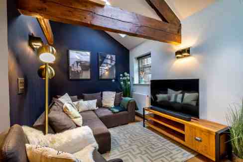 Bright living room with modern decor and wooden beams at Clementhorpe Apartments. Comfortable seatin.