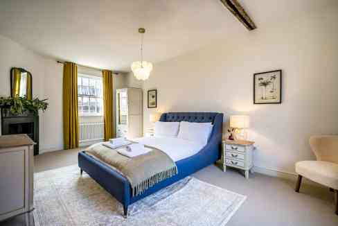 Bedroom with blue upholstered bed and elegant decor.