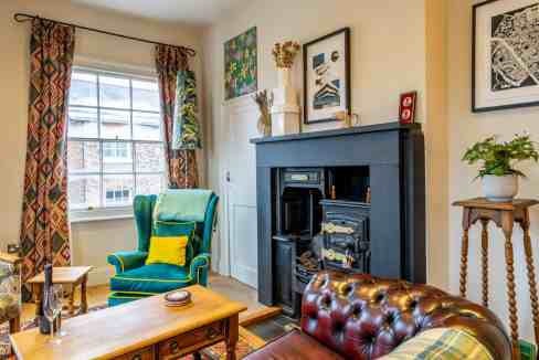 Charming interior of a living room featuring a fireplace, colorful armchair, and decorative artwork.