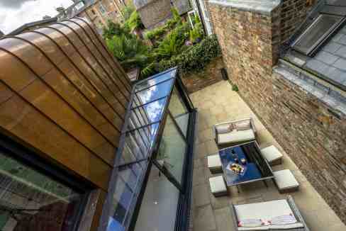 Outdoor patio with modern seating and glass conservatory at Clifford's Townhouse.