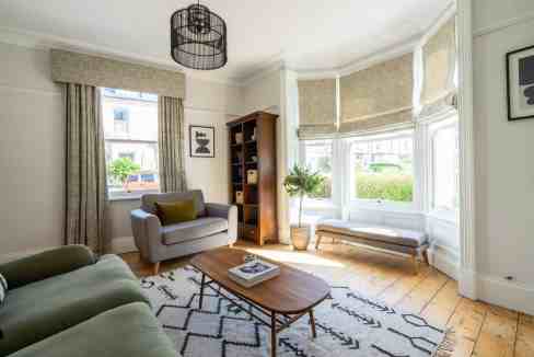 Bright living room with large bay windows and stylish decor at Scarcroft Road Apartments.