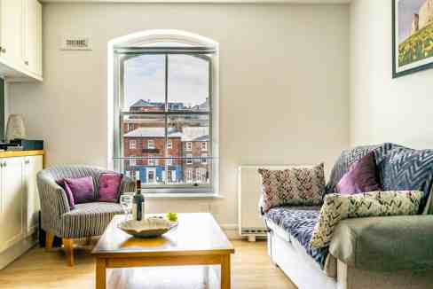 Bright living room with large window overlooking historic buildings at Woodsmill Quay Apartments.