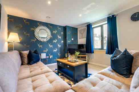 Living room with beige sofas and blue accents, featuring a patterned wallpaper and modern decor.