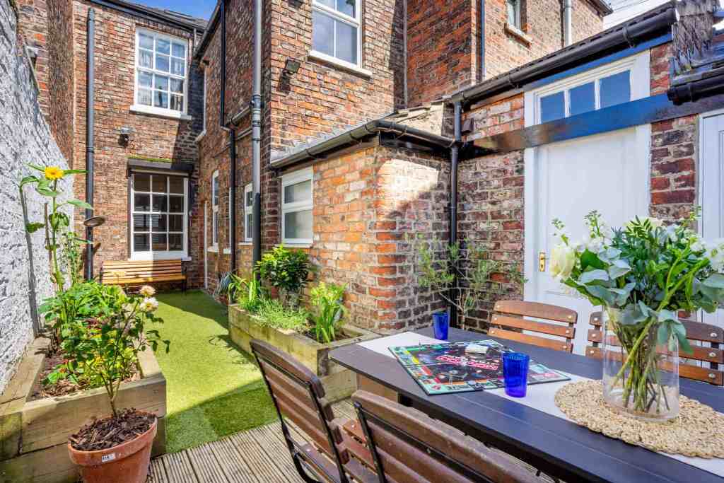 Cozy outdoor patio of Bishophill Senior Cottage with garden furniture and lush greenery.