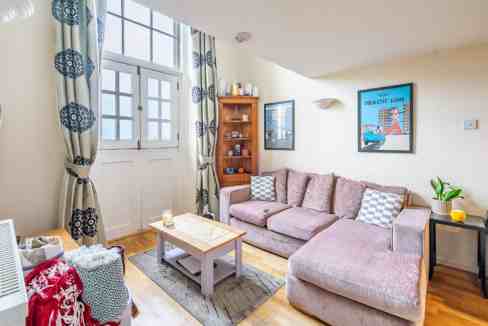 Bright living room with pink sofa, wooden accents, and large window in York County House.