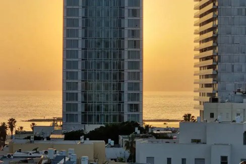 View of Jerusalem Beach Apartments with ocean sunset in background.