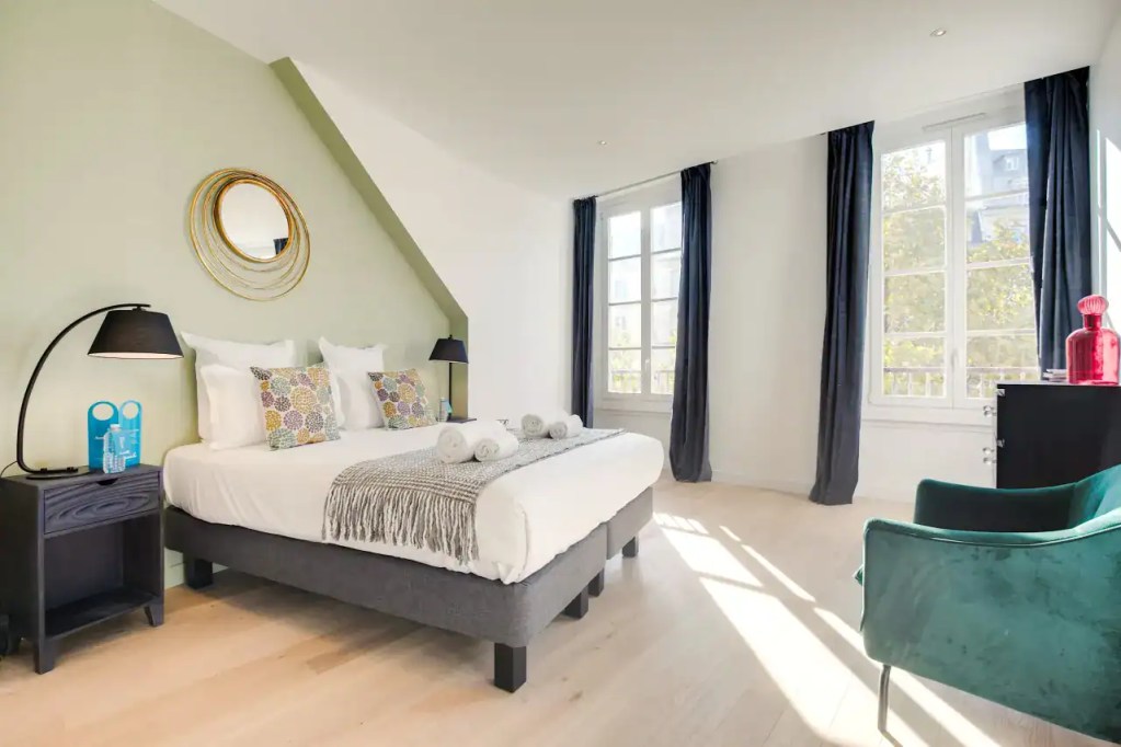 Bright bedroom at Bonne Nouvelle Apartments with large windows and modern decor.