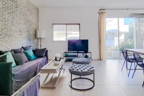 Bright and spacious living room with contemporary furniture and natural light at Hovevei Tsiyon Apar.