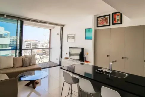 Modern apartment living room with large windows and city views.