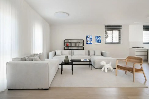 Spacious living room with white sofa, contemporary art, and natural light.