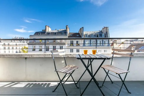 Balcony view of Strasbourg Saint-Denis apartments with outdoor table and chairs under a clear blue s.