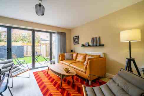 Bright living room with large glass doors opening to a garden.