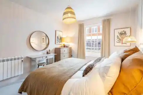 Bright bedroom with large window, neutral decor, and warm lighting at Bridge St Apartments.
