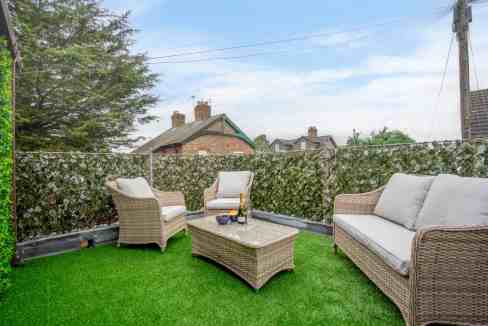 Outdoor seating area at York Racecourse House with wicker furniture and lush green artificial grass.