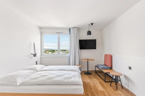 Bright Vienna apartment room with bed, window view, and minimal decor.