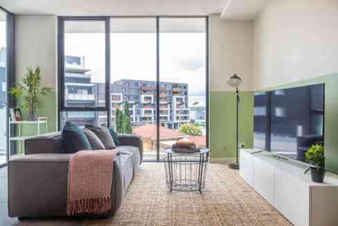 Bright living room with spacious windows overlooking cityscape at Mays Hill Apartments.