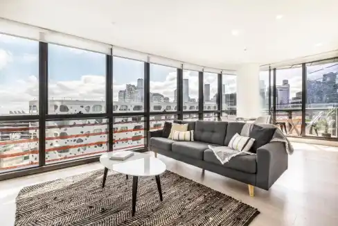 Apartment living room with large windows overlooking Melbourne Docklands skyline.