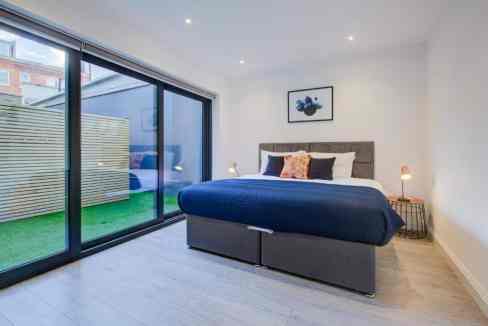 Spacious bedroom in Fulham Road Apartments featuring large glass doors opening to a private outdoor.