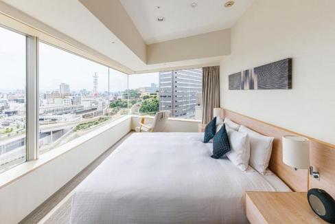 Aparthotel room in Osaka Namba with a spacious bed and panoramic city views.